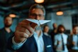 A man holding a paper airplane in front of a group of people. Ideal for business presentations
