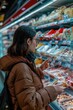 © Fotograf - A woman examining a display of food in a store. Suitable for grocery store or healthy eating concepts