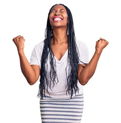 Sticker - Young african american woman wearing casual clothes very happy and excited doing winner gesture with arms raised, smiling and screaming for success. celebration concept.