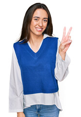 Poster - Young hispanic girl wearing casual clothes smiling with happy face winking at the camera doing victory sign. number two.