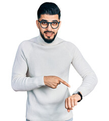 Wall Mural - Young arab man with beard wearing elegant turtleneck sweater and glasses in hurry pointing to watch time, impatience, upset and angry for deadline delay