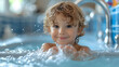 Close up portrait of ten year old boy enjoying in a swimming pool, looking at camera smiling