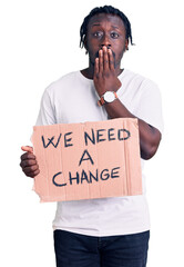 Poster - Young african american man with braids holding we need a change banner covering mouth with hand, shocked and afraid for mistake. surprised expression