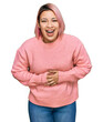 © Krakenimages.com - Hispanic woman with pink hair wearing casual winter sweater smiling and laughing hard out loud because funny crazy joke with hands on body.