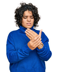 Canvas Print - Young hispanic woman with curly hair wearing turtleneck sweater suffering pain on hands and fingers, arthritis inflammation