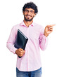 © Krakenimages.com - Handsome young man with curly hair and bear holding business folder smiling happy pointing with hand and finger to the side