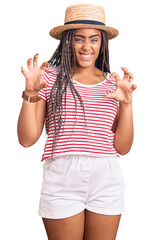 Wall Mural - Young african american woman with braids wearing summer hat smiling funny doing claw gesture as cat, aggressive and sexy expression