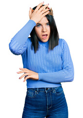 Poster - Young brunette woman with blue eyes wearing princess crown surprised with hand on head for mistake, remember error. forgot, bad memory concept.