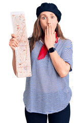 Wall Mural - Young beautiful blonde woman wearing french beret holding city map covering mouth with hand, shocked and afraid for mistake. surprised expression