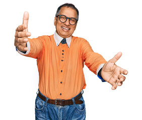 Sticker - Middle age indian man wearing casual clothes and glasses looking at the camera smiling with open arms for hug. cheerful expression embracing happiness.