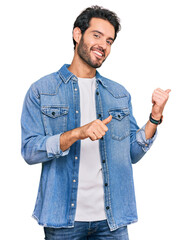 Wall Mural - Young hispanic man wearing casual clothes pointing to the back behind with hand and thumbs up, smiling confident