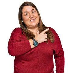 Wall Mural - Beautiful brunette plus size woman wearing casual clothes cheerful with a smile of face pointing with hand and finger up to the side with happy and natural expression on face