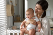© New Africa - Happy young mother with her baby near window at home. Space for text