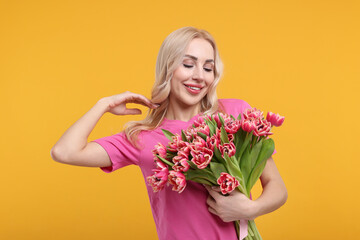 Wall Mural - Happy young woman with beautiful bouquet on orange background