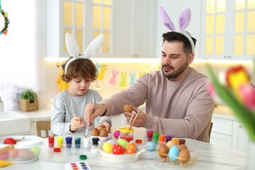 Canvas Print - Easter celebration. Father with his little son painting eggs at white marble table in kitchen