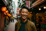 Fototapeta Fototapeta uliczki - Portrait of a handsome young Asian man smiling while walking down a narrow street in a city.