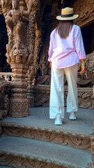 Wall Mural - A lady in a sun hat casually climbs the wooden stairs of a temple, enjoying the leisurely travel experience and the scenic landscape around her, Pattaya, Sanctuary of Truth Temple, Thailand