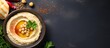 A visually appealing display of hummus spread with bread and parsley on a sleek black background, emphasizing a concept of tasty food from a top-down perspective
