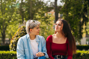 Wall Mural - two teenager girls sitting in a park talking