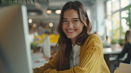 Wall Mural - Smiling woman sitting at a desk with a laptop computer