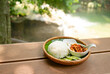 Stir-fried rice with basil, Thai food, Put in a classic wooden plate with a view of a waterfall and green trees in the background.