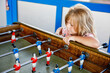 Little preschool girl playing table soccer. Happy excited positive child having fun with family game with siblings or friends.
