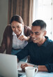 © peopleimages.com - Couple, laptop and happy with finance in kitchen for savings profit, debt review or good credit score. Documents, people and technology with smile for mortgage payment, insurance policy or budgeting