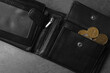 Poverty. Black wallet and coins on grey table, top view