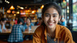 Joyful young Asian woman smiling warmly in a sociable cafe setting.