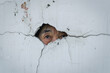 A person peeking through a crack of a wall