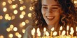 A woman with curly hair smiles as she blows out candles on a birthday cake