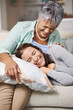 © peopleimages.com - Elderly, mom and laugh with daughter on sofa with pillow for happiness in retirement for bonding with happy. Mature, woman and couch with together in living room in family home for relax with care