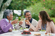 © peopleimages.com - Senior, parents and woman in garden, champagne and outdoor for celebration of anniversary for elderly couple. Summer, relax and healthy food and salad with cake for lunch or brunch with family