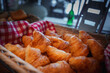 Close up view of golden brown freshly baked croissants in a basket lined with red and white cloth, likely in a luxury hotel in Zermatt, a Swiss ski resort.