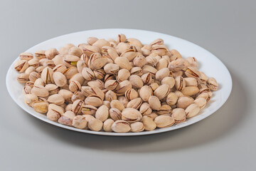 Wall Mural - Roasted pistachio nuts on dish on gray background, side view