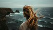 a girl stands on the ocean shore, and the wind blows her hair