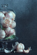 Garlic Bulbs Elegantly Displayed in a Glass Cloche. An assortment of garlic bulbs showcased in a transparent glass cloche, adorned with rosemary.