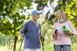 © Liubomir - Senior smiling couple, gray-haired man and woman doing sports in the park. Standing holding trekking poles, mat and water, talking to each other.