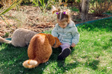 Fototapeta Do akwarium - Cute child girl feed cats in spring backyard garden