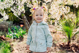 Fototapeta Do akwarium - Smiling beauty girl in jacket in spring blooming garden.