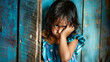 A little offended sad girl stands in front of a solid blue wall and looks directly expression. Child psychology. Relationship between parents and children. Banner. Copy space