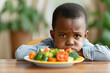Little african american boy's aversion to salad evident in his unhappy expression