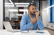 © Tetiana - Indian man using an inhaler for asthma in the office