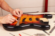 Guitar master measures size of holes for tremolo in body of guitar with ruler.