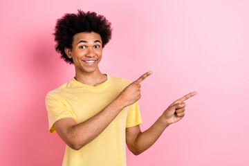 Photo of charming sweet guy dressed yellow t-shirt pointing two fingers empty space isolated pink color background