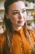 Close-up portrait of an elegant woman against the background of shelves with ceramic dishes. Elegant woman ceramic artist in a cozy studio Head shot, atmospheric portrait