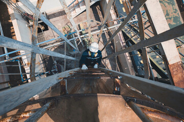 Wall Mural - Top view male worker climbs up the ladder inspection stainless tank work at height