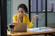 © Wasana - Distressed young businesswoman feeling pressure and headache at her office desk with laptop and documents.