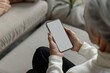 Ui mockup through a shoulder view of a elderly woman holding an smartphone with an entirely grey screen