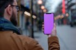Digital mockup over a shoulder of a man holding an smartphone with a completely purple screen